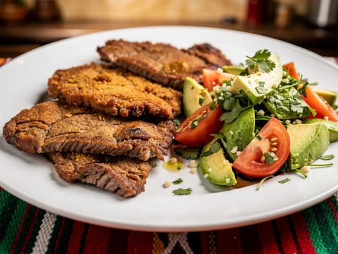 Milanesa de Res (bistecche di manzo impanate) con insalata di pomodoro e avocado