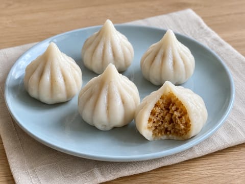 Modak (gőzölt rizslisztes gombócok kókuszos-jaggery töltelékkel) Modak (gőzölt rizslisztes gombócok kókuszos-jaggery töltelékkel)