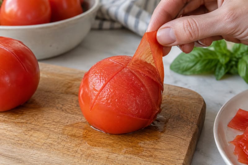 Löst tomatskal dras bort från ett grunt kryssnitt.